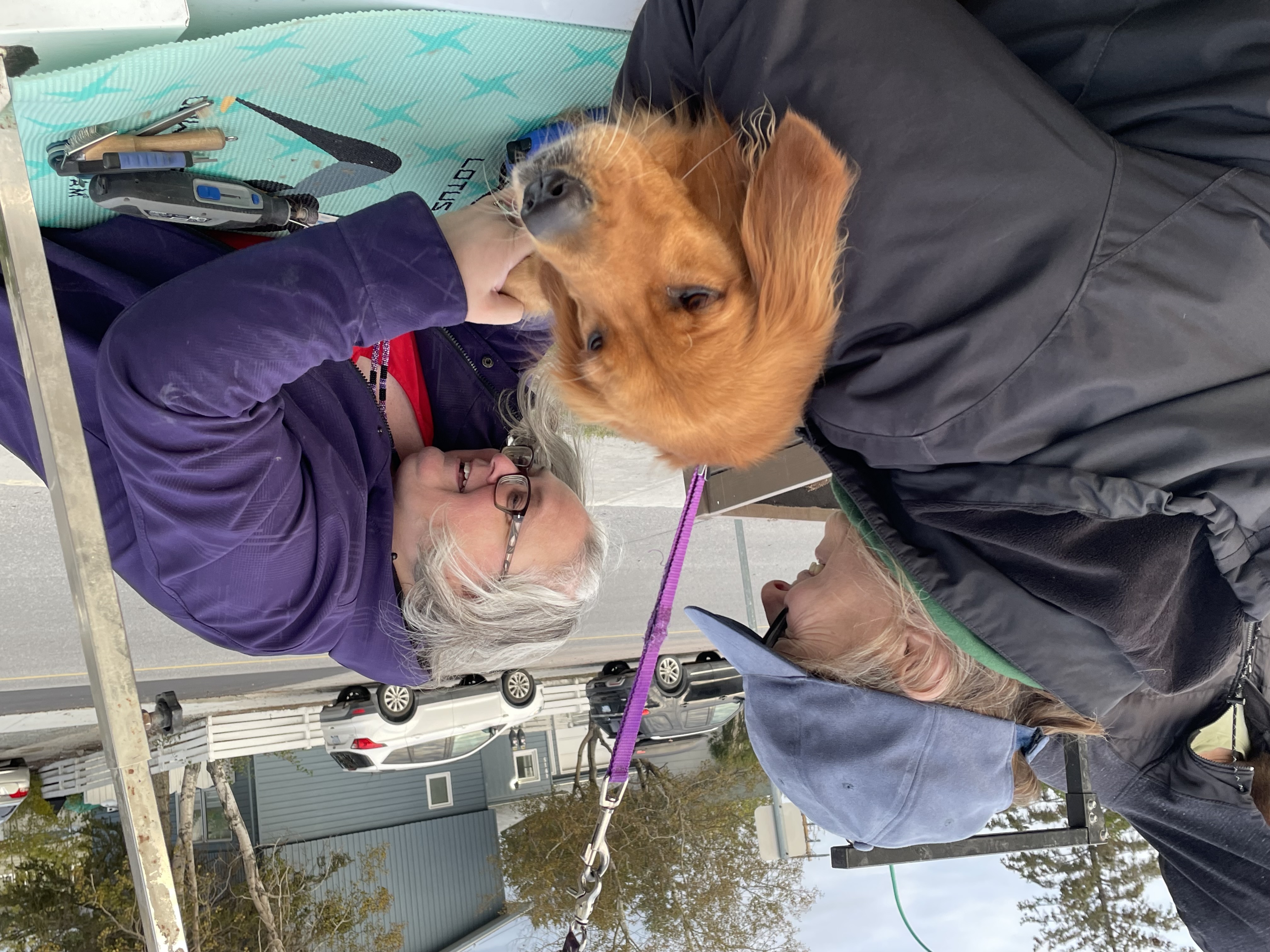 Two men outdoors, one holding a curly dog.